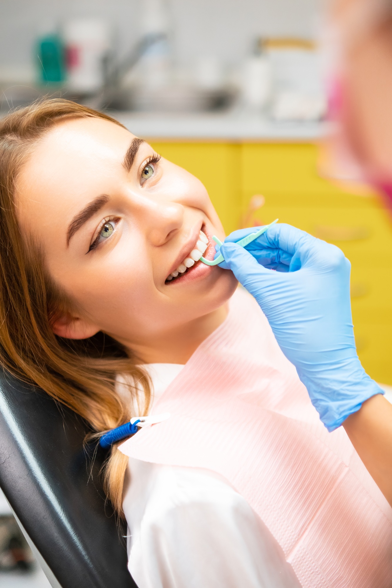 A dentist cleaning teeth with a plastic dental floss to the patient.