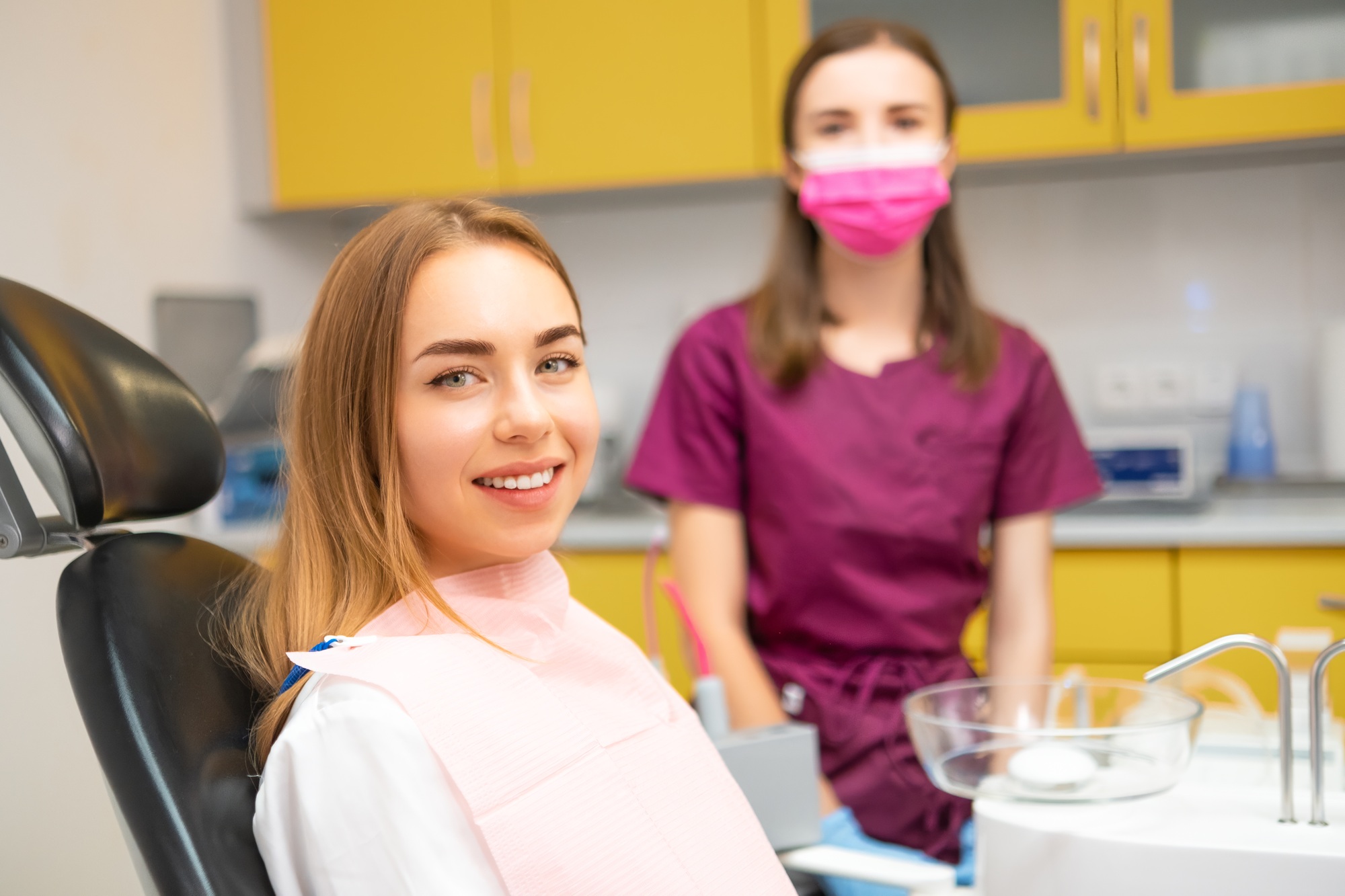 Happy young woman patient smilling sitting in medical chair at dental clinic.